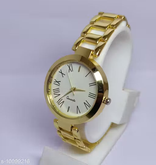 A gold-tone metal watch with a white dial and Roman numeral hour markers, displayed on a white stand against a light lavender background.